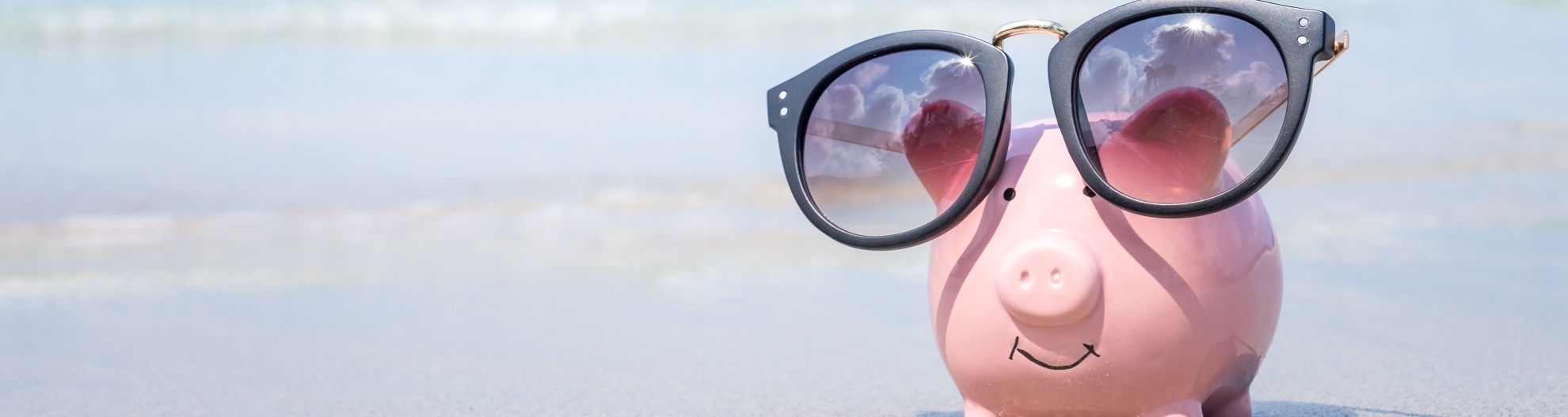 Saving money for travel concept, pink piggy bank wearing sunglass on the beach 