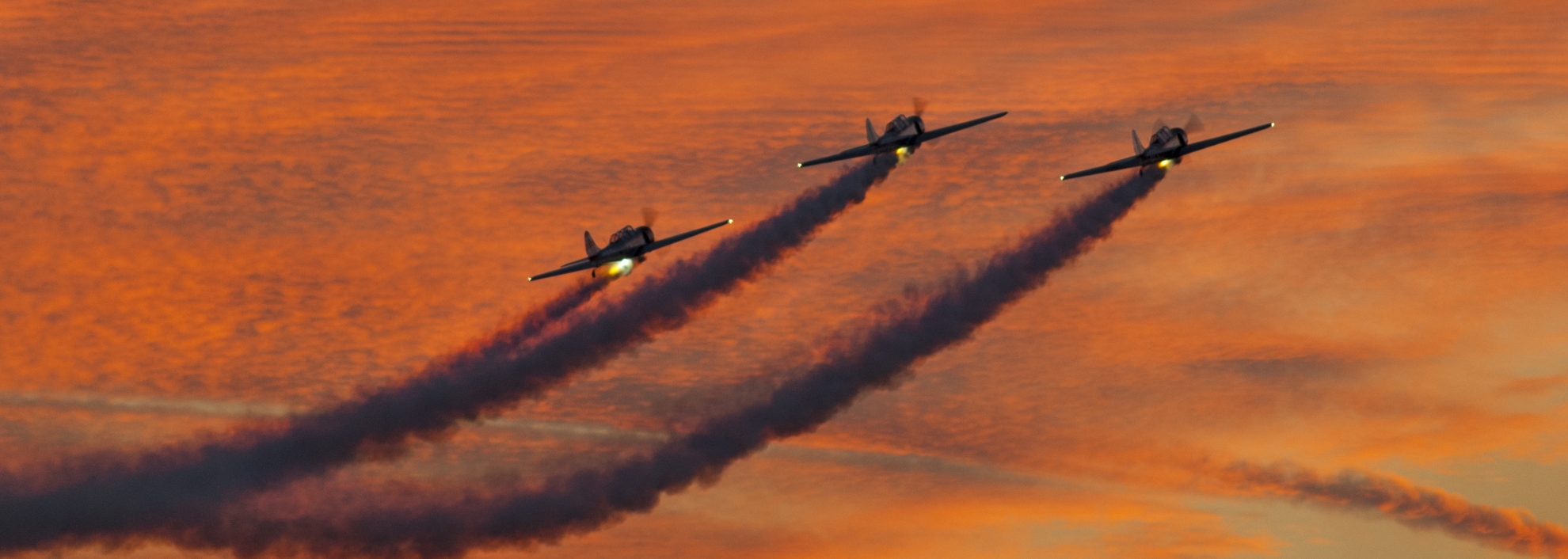 Single engine planes with Smoke trails at dusk