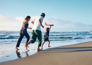 Parents running behind a boy running straight ahead with a model airplane held high in one hand